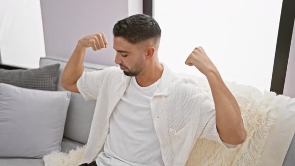 Selvsikker Ung Arabisk Mann Som Sitter Sofaen Flaunting Muskuløse Armer – stockvideo