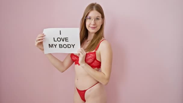 穿着红色内衣的自信女性在粉色背景下有一个身体阳性标志 这代表了她的自爱和自强 — 图库视频影像