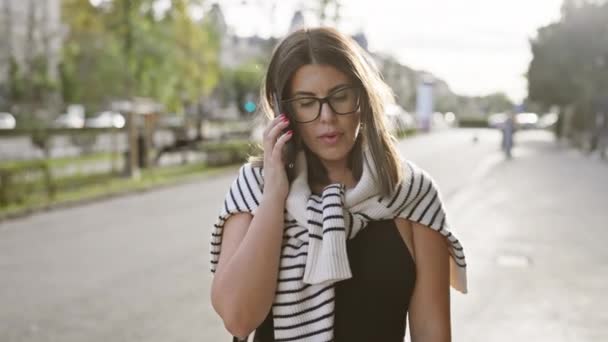 Молодая Женщина Разговаривает Мобильному Телефону Идя Солнечной Улице Budapest Олицетворяя — стоковое видео