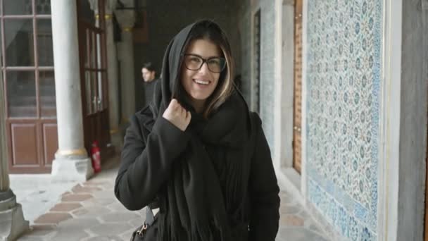 イスタンブールの歴史的なトップカピ宮殿でメガネとスカーフで笑顔の若い女性 旅行と美しさを伝える — ストック動画