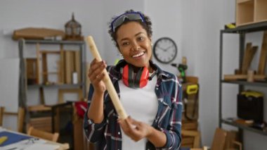 Genç bir kadın yaratıcı marangozluk atölyesindeki keresteleri inceliyor..