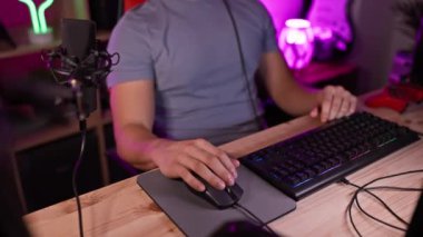 Genç bir İspanyol adam, gece renkli bir oyun odasında kulaklıkları ve mikrofonuyla rahatlıyor..