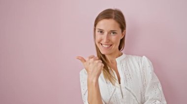 Pembe arka planda duran neşeli genç bir kadın, başparmağını kaldırmış, parlak bir gülümsemeyle ürünü gösteriyor..