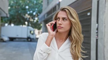 Havalı sarışın kadın, genç ve güzel, Sunny City caddesinde ciddi bir akıllı telefon konuşmasına dalmış, rahat bir konsantrasyon ve gündelik, çekici bir yaşam tarzı sergiliyor..