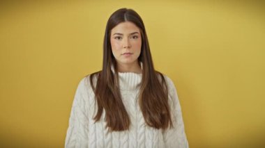 Genç, güzel İspanyol kadın dudaklarını sessizce kapatıyor. İzole edilmiş sarı arkaplan üzerinde sessiz iletişim ve gizlilik ifadesi