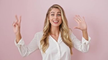 Neşeli genç sarışın, 7 numarayı sembolize etmek için parmak kaldırıyor pembe izole edilmiş arka planda pozitif bir ifadenin portresi.