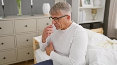 Orta yaşlı, gri saçlı, pijamalı, yorgun gözlerini ve burnunu yatak odasına sürten bir adam. baş ağrısı, yorgunluk, stres, hayal kırıklığı, stresli bir günün belirtileri?