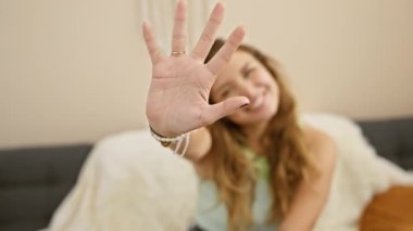 Kendinden emin bir şekilde beş parmağını gösteriyor. Günlük giysiler içindeki genç ve güzel bir İspanyol kadın evinin rahatlığında sevinçlerini ifade ediyor..