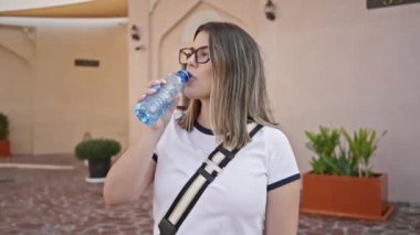 Genç bir kadın, içme suyu, geleneksel bir Arap ortamında duruyor, seyahat, kültür ve doha, katar boş zamanlarını öneriyor..