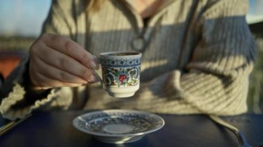 Genç kadın İstanbul Kafe 'de geleneksel Türk kahvesi içiyor, güneş ışığı fincanı tasarımı.