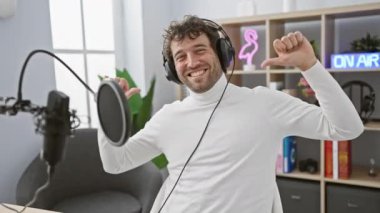 Hiçbir şeyden haberi olmayan, kulaklık takmış, radyo stüdyosunda omuz silkiyor. Şaşırmış yüz ifadesi, eller yukarı. Cevabı biliyor mu bari?