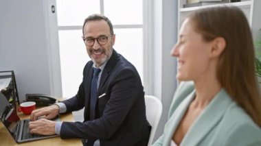 İki rahat iş adamı ellerini başlarının üstüne koyup rahatça dinleniyorlar. Dizüstü bilgisayarda birlikte çalışırken gülümsüyorlar.