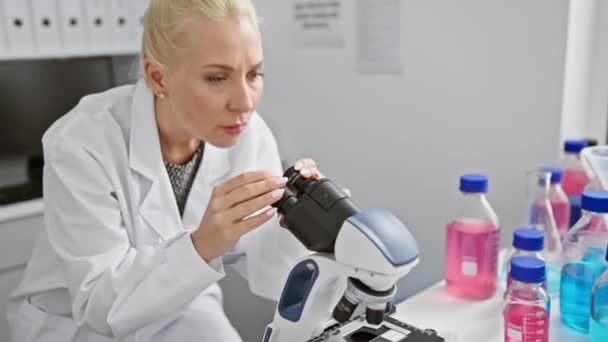 年轻的金发女人皱着眉头 穿着科学家制服在实验室里 挣扎着解决一个难题 满脸疑惑 心烦意乱 神经紧张 — 图库视频影像