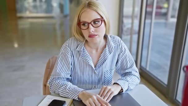 Thoughtful Woman Blonde Hair Red Glasses Sitting Table Indoors Notebook — Stock Video