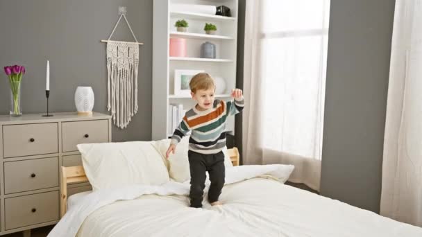 楽しい幼児の少年が居心地の良い家の寝室でベッドで演奏し 屋内でケアフリーの子供時代の瞬間を描いています — ストック動画