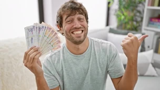 Glada Ung Man Hemma Tryggt Hålla Colombian Pesos Peka Tummen — Stockvideo