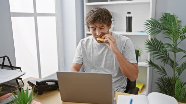 Przystojny Hiszpan Brodą Jedzący Podczas Pracy Laptopie Nowoczesnym Biurze — Wideo stockowe