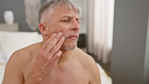 一个白发苍苍的男人在卧室里审视自己的脸 反映出对衰老和护肤的担忧 — 图库视频影像
