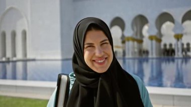 Arka planda geleneksel İslami mimarisi olan Abu Dabi Camii 'nde tesettürlü bir kadın..