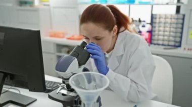 Parlak bir laboratuvar ortamında mikroskop kullanarak numuneleri analiz eden profesyonel bir kadın bilim adamı.
