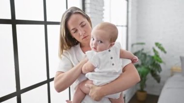 Anne evde kollarında kızıyla dikiliyor.