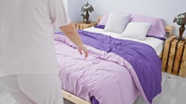 Neşeli, rahat bir yatak odasında tüylü köpeğiyle oynaşan genç bir kadın..