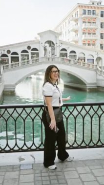 Tarz sahibi genç bir kadın, Doha 'nın Qanat Quartier' inin modern mimarisinden zevk alıyor, şehir merkezindeki orta doğu manzarasında seyahat ve moda sergiliyor..