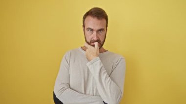 Endişeli orta yaşlı İspanyol bir adam, strese girmiş ve tırnaklarını yiyor, sarı arka plana karşı tek başına duruyor, gerçek endişe sorununu ortaya çıkarıyor..