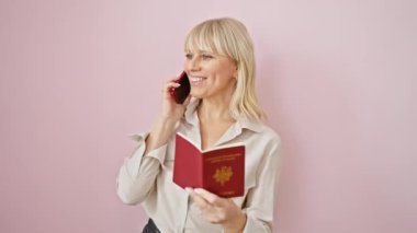 Gülümseyen, sarışın bir kadın, elinde Fransız pasaportuyla cep telefonuyla konuşuyor..