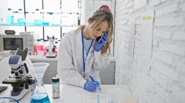 Modern bir laboratuvarda çalışan ve birden fazla iş yapan odaklanmış bir kadın bilim adamı.