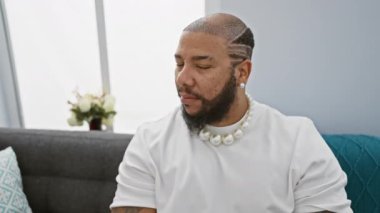 Kendinden emin ve yakışıklı Afro-Amerikan adam koltuğundan dişleriyle gülümsüyor. Mutlu, sağlıklı gülümsemesini sunarken dairesi pozitif, neşeli titreşimler yayıyor.!