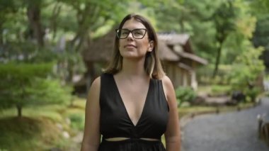 Neşeli, başarılı, gözlüklü İspanyol bir kadının göz kamaştırıcı fotoğrafı. Kyoto 'daki klasik Kodaiji tapınağına neşe içinde bakıp poz verirken mutluluk saçıyor.