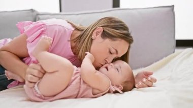 Neşeli anne kanepede uzanıyor, evde mutlu kızı öpüyor, güzel bir yaşam tarzı paylaşıyor.