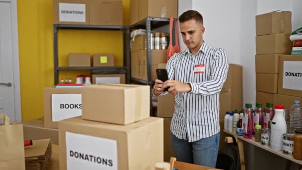 Focused Young Man Using Smartphone Warehouse Labeled Donation Boxes Assorted — Stock Video