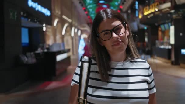 Uma Mulher Sorridente Com Óculos Uma Camisa Listrada Posa Dentro — Vídeo de Stock