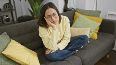 Sıkılmış ve yorgun, gözlük takan genç bir İspanyol kadın evdeki depresyon ifadesini tasvir ediyor. Kollarını kavuşturmuş, oturma odasında derinden sorunlarını düşünüyordu..
