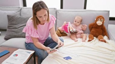 Stresli anne aile sevgisinin ortasında hesap işleriyle uğraşırken, kız evdeki oturma odasındaki kanepede oyuncak bebeklerle şakalaşıyor.