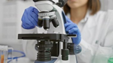 Laboratuvar ortamında tıbbi araştırmalar için mikroskop kullanan laboratuvar önlüklü bir bilim adamı..