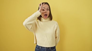 İspanyol güzeli şokta! Süveter giyen genç kadın işaret veriyor, sarı duvardaki parmakların arasından bakıyor..