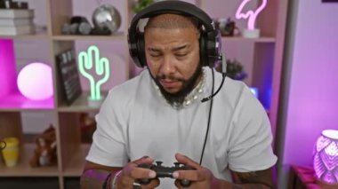 Odaklanmış, sakallı bir Amerikalı gece vakti renkli ışıklı bir odada oyun oynuyor..