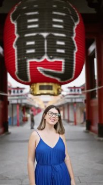 Neşeli, güzel, gözlüklü İspanyol bir kadın görkemli Senso-ji tapınağını zevkle keşfediyor ve hayranlıkla seyrediyor. Öylesine geziniyor, hayranlıkla etrafa bakıyor ve kendine güvenen bir gülümsemeyle..