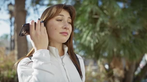 若い女性は緑の公園で屋外のボイスメールを聞く — ストック動画