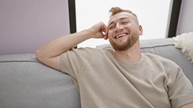 Neşeli, sakallı genç bir adam. Kapalı bir koltukta dinleniyor. Tarafsız, modern bir dekorla mutluluğu ve rahatlığı ifade ediyor..