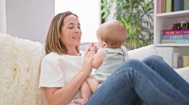 Anne kızıyla oynuyor. Evdeki kanepede oturuyor.