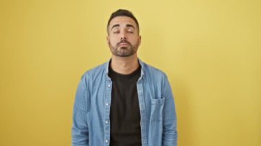 Kot gömlek giyen genç İspanyol adam uykulu ve yorgun görünüyor, yorgunluktan bitkin ve akşamdan kalma, sabahları tembel gözler. izole edilmiş sarı arkaplan