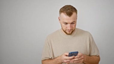 Sakallı yakışıklı bir genç, beyaz bir arka planda akıllı telefonuyla mesajlaşırken gülümsüyor..