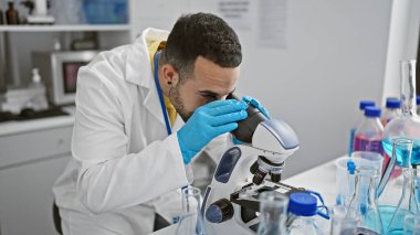 İspanyol bilim adamı laboratuvar ortamında mikroskop kullanarak örnekleri analiz ediyor.