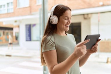 Genç ve güzel bir kadın gülümsüyor. Sokakta dokunmatik bir yerde video izliyor.