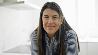 Genç ve güzel İspanyol kadın mutfakta mutlu gülümsüyor.