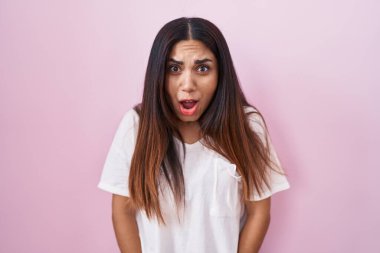 Pembe arka planda duran genç Arap kadın şaşkınlık ve şaşkınlık dolu ifade, korku ve heyecan dolu yüz ifadesiyle dehşete düşmüş ve şok olmuştu.. 